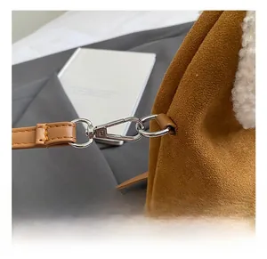 Détail du crochet en argent et de la bandoulière en daim marron avec fausse fourrure