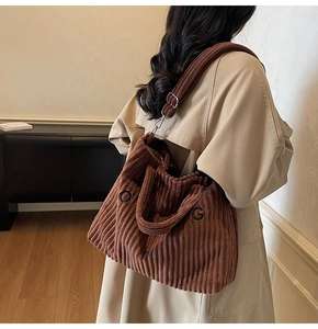 Detailed view of large brown corduroy tote bag with OG embroidery on khahi trench coat