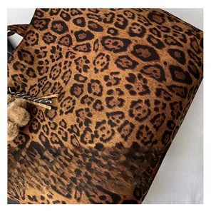 Detail of leopard print tote bag featuring a brown faux fur pompom and soft plush texture