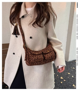 Detail of leopard print baguette bag featuring dual front pockets with gold metal snaps