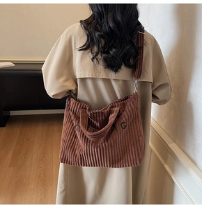 Detailed close-up of brown corduroy tote bag showing 'BAG' embroidery and soft texture