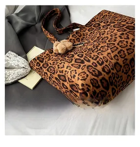 Detail of leopard print tote bag with plush pom-pom charm and thick velvet texture