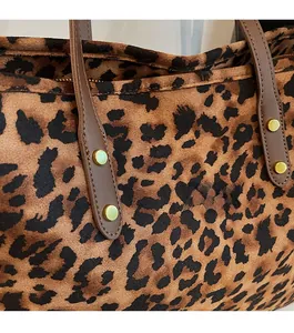 Detail of leopard print faux suede tote bag with brown leather handle and gold rivet
