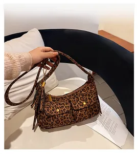 Close-up of leopard print baguette bag with twin front pockets and hanging tassels