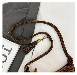 Detailed macro view of leopard print baguette bag with fringe tassel and gold hardware