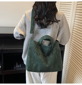 Detail view of dark green corduroy tote bag showing thick texture and embroidery