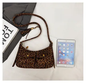 Leopard print baguette bag with twin front pockets and tassel detail next to an iPad