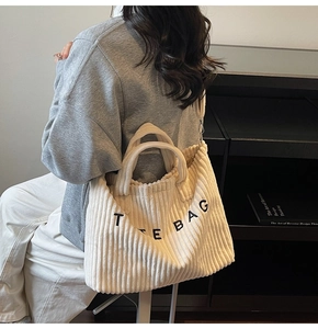 Detail of cream corduroy tote bag with black letter print on a stylish shoulder model