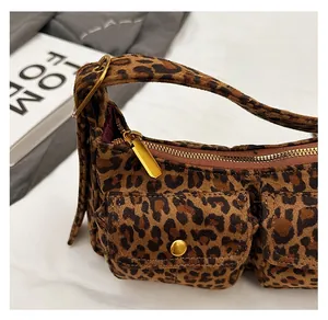 Detailed close-up of smooth gold metal zipper and double front pockets on leopard baguette bag