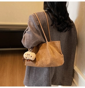 Close-up of brown suede tote bag with a cute sheep charm and leather shoulder straps