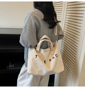 Detail of off-white corduroy tote bag showing vertical texture and THE BAG embroidery