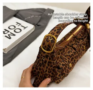 Detail of leopard print baguette bag featuring adjustable bronze buckle and zipper closure