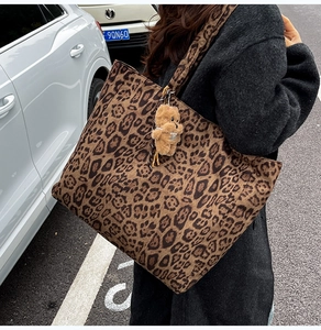 Chic leopard print faux suede tote bag with plush bear charm worn over the shoulder