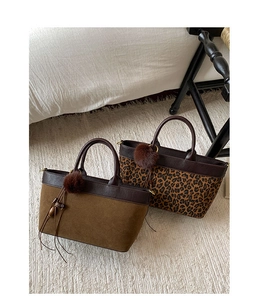 Detail of brown suede and leopard print tote bags with fuzzy pompom and fringe charms