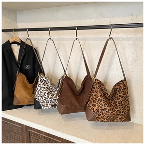 Detail view of large leopard print tote bags in suede and leather with woven stitching