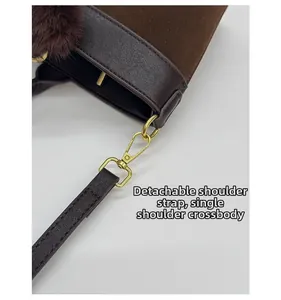 Detail of detachable brown shoulder strap with golden hooks on contrast tote bag