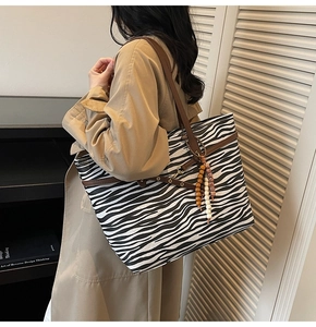 Detail of zebra pattern tote bag with brown leather straps and beaded tassel charm