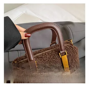 Detail view of plush brown faux lambskin handbag with leather handle and gold hardware