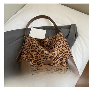 Macro detail of leopard print tote featuring brown leather strap and stitching details