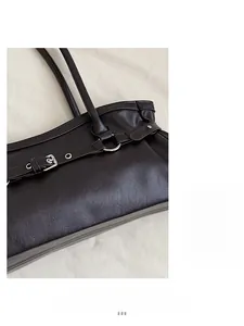 Gros plan du sac baguette en cuir marron foncé mat avec boucle argentée et rivets détaillés