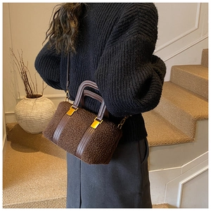 Detail of dark brown faux fur Boston bag with gold hardware held by model in autumn style