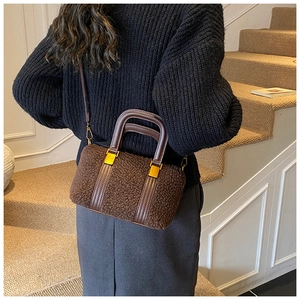 Detail of plush brown shearling crossbody bag with leather handles and gold metal hardware