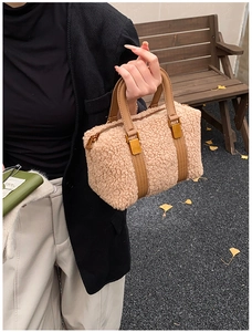 Detail of plush fleece Boston bag with brown leather handles and golden metal hardware
