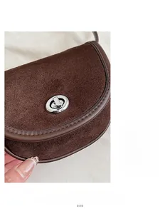 Detail of dark coffee frosted leather saddle bag with silver metal swivel lock