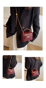 Detail view of the wine red quilted mini bag with gold chain and dual zipper closures
