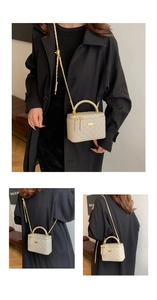 Detail view of beige quilted vanity bag with metal handle and gold chain strap