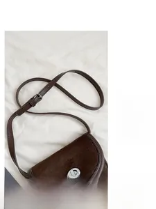 Detail of vintage dark brown saddle bag showing suede texture and silver twist lock