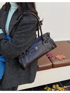 Détail du sac à bandoulière rétro marron foncé avec boucle en métal sur manteau gris