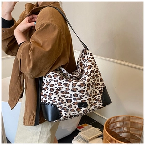 Detail of leopard print tote bag featuring canvas fabric and black leather corners