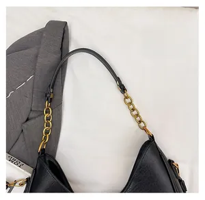 Nahaufnahme der schwarzen Ledertasche mit Litschi-Struktur und goldener Ketten-Details