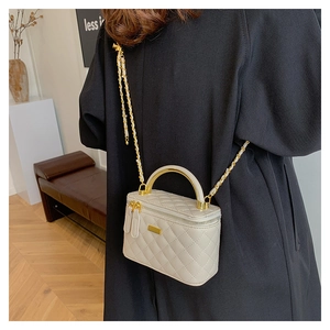 Detail of white quilted crossbody bag with gold chain strap and metal top handle