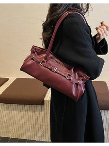 Détail du sac baguette en cuir bordeaux avec boucle en métal et texture plissée