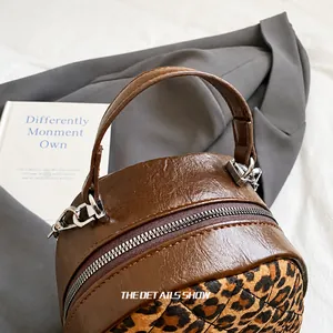 Détail d'un mini sac à dos avec imprimé léopard et poignée en cuir synthétique marron