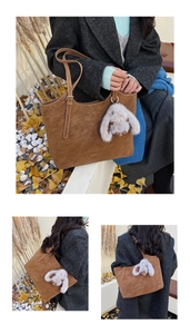 Detail of brown faux suede tote bag with long-ear rabbit charm and stitching