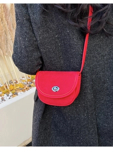 Close-up of red matte saddle bag with silver twist lock on a wool coat outfit