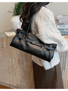 Détail du sac baguette en cuir noir avec boucles argentées vintage et style industriel