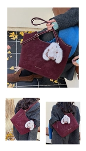 Close-up of burgundy tote bag with plush rabbit charm and fashion text detail