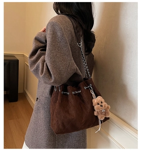 Detail of dark brown quilted drawstring bucket bag with silver chain and cute bear charm