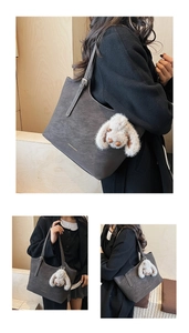 Detail view of dark grey suede tote bag with gold lettering and plush rabbit charm
