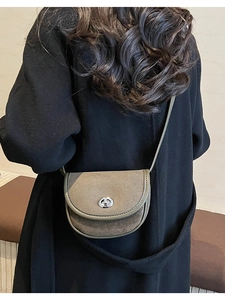 Detail of vintage suede saddle bag featuring a metallic swivel lock and neat stitching