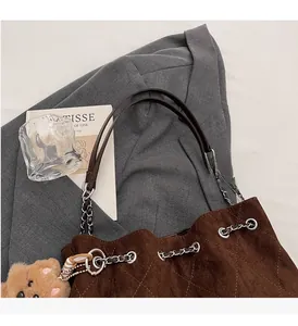 Detail of dark brown suede tote featuring quilted pattern and silver chain handles