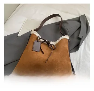 Close-up of brown suede hobo bag with white faux shearling trim and leather handle