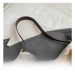 Detailed close-up of brown suede shoulder bag with white faux fur trim and leather strap