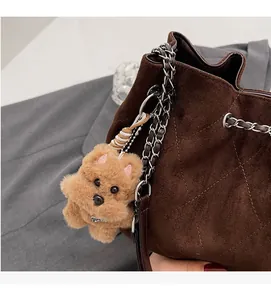 Detail of dark brown suede bucket bag with diamond stitching and bear charm