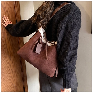 Detail of suede tote bag with white faux fur trim and leather drawstring closure