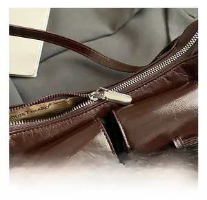 Macro shot of dark brown glossy leather bag featuring silver zipper and bow detail